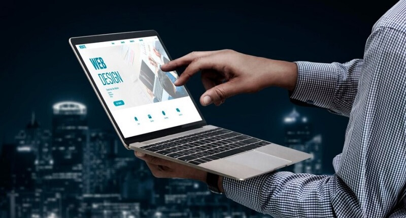 man holding laptop and web design software on screen