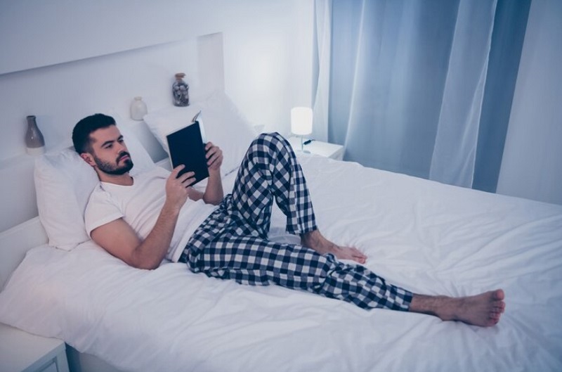man reads book in night wear