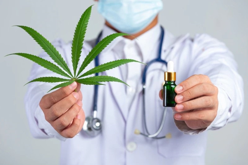 doctor-holding-cannabis-leaf-and-bottle-of-oil